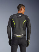 Alpinestars GP Force V2 Air Leather Jacket, Black and Yellow Fluo, back view of a male rider showing extensive perforated leather panels for airflow, white Alpinestars branding and yellow "Racing Ahead" text on the lower back, sport motorcycle gear for road riding.
