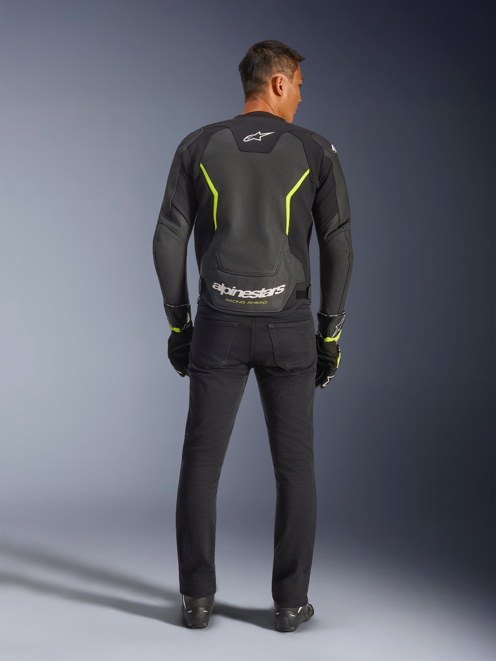 Alpinestars GP Force V2 Air Leather Jacket, Black and Yellow Fluo, back view of model wearing the sport motorcycle jacket, featuring large perforated sections, neon yellow accents, and white 'alpinestars' branding on the lower back, paired with black riding gear