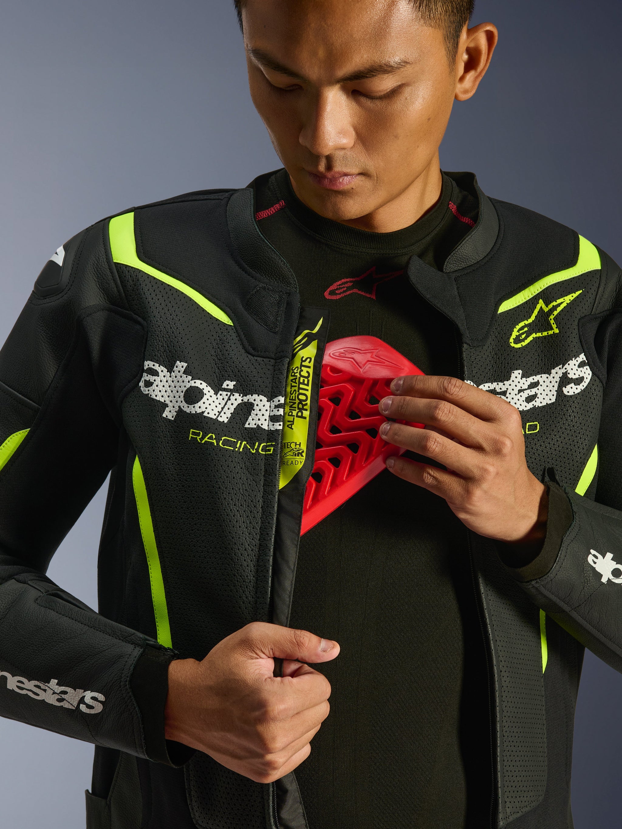 Alpinestars GP Force V2 Air Leather Jacket, Black and Yellow Fluo, perforated leather motorcycle jacket, worn by a rider demonstrating the chest compartment with a red protector insert, featuring white Alpinestars branding and extensive airflow perforations.