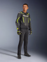 Male model wearing Alpinestars GP Force V2 Air Leather Jacket in Black and Yellow Fluo, paired with black riding pants, matching gloves, and black shoes, full-body studio shot of sport motorcycle gear featuring perforated leather and bold branding