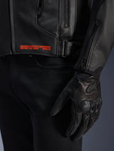 Alpinestars GP Plus V4 Leather Jacket, Black, close-up of side detail with orange branding text 'ADVANCED RACEWEAR ENGINEERING', adjustable buckle, and black leather riding glove, sport motorcycle apparel