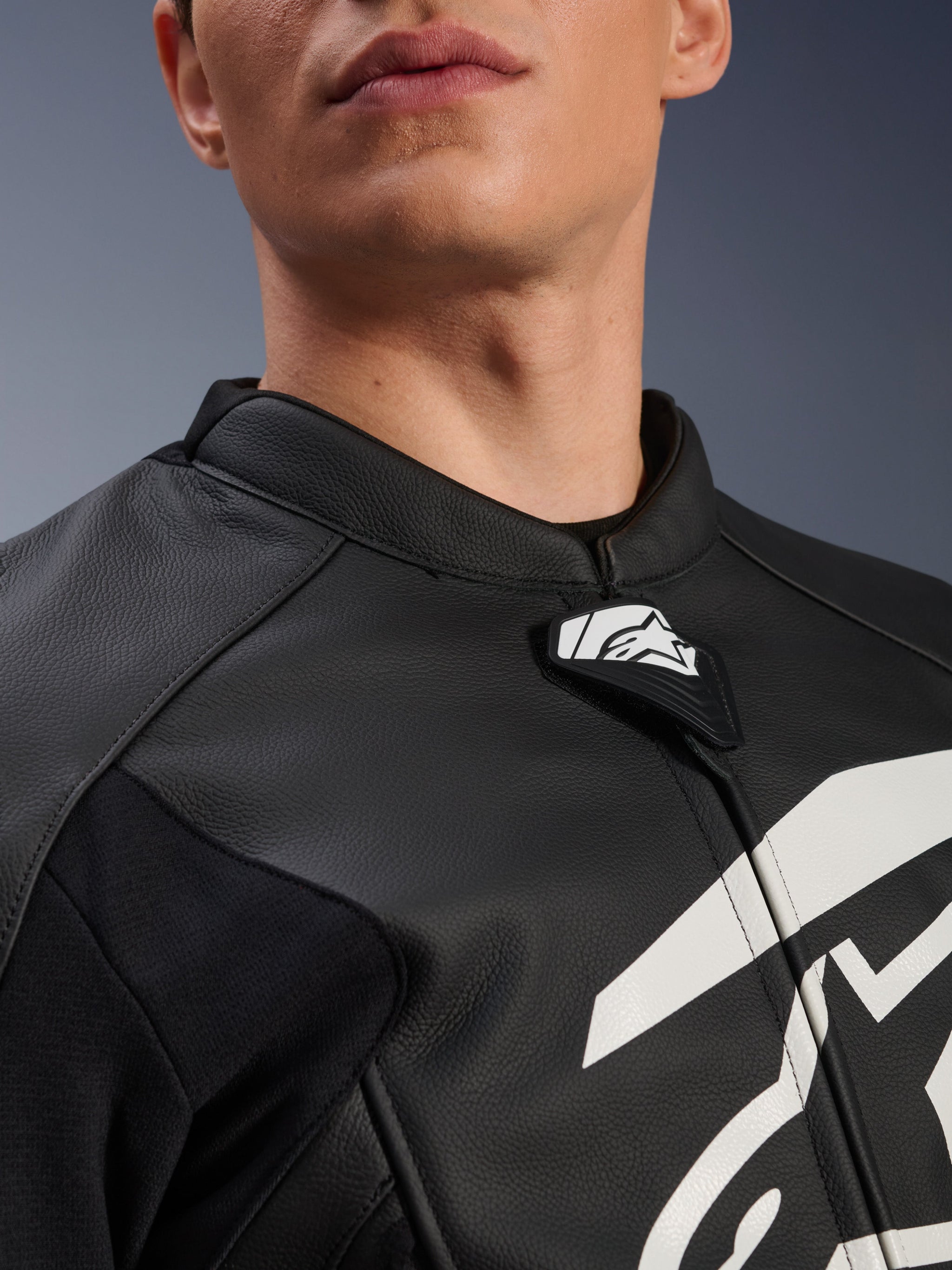 Alpinestars GP Plus V4 Leather Jacket, Sport Motorcycle Jacket, Black and White, close-up of textured leather collar and Alpinestars logo tab, white graphic on chest, race-derived design