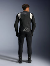 Alpinestars Dusk Airflow Leather Jacket, Black and White, rear view of a rider wearing black pants and boots, featuring perforated leather for ventilation, white accordion stretch panels on the shoulders, and white branding on the lower back