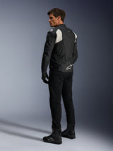 Alpinestars Dusk Airflow Leather Jacket, Black and White, rear view of model wearing the perforated leather jacket with matching black pants and boots, featuring white accordion stretch panels and bold logo on the lower back, sport motorcycle riding gear