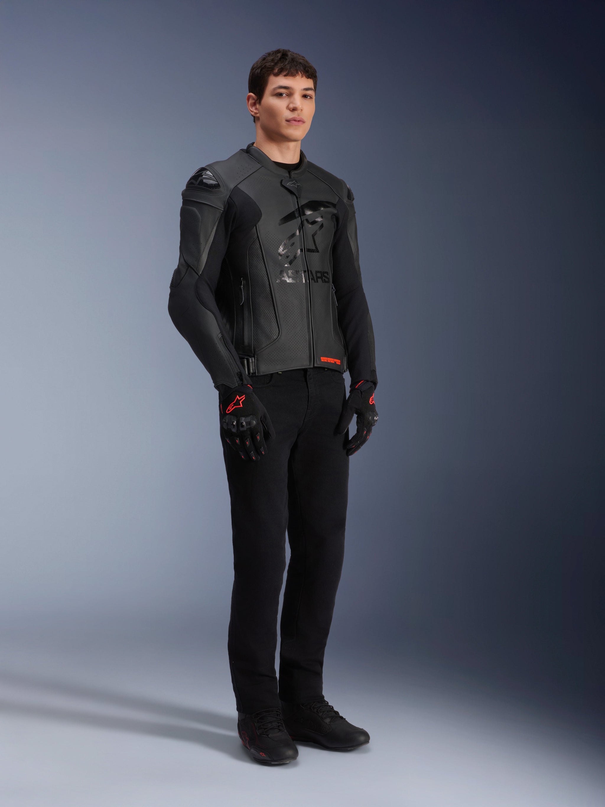 Alpinestars GP Plus R V4 Airflow Leather Jacket, Black, worn by a male model with black riding pants and gloves with red accents, featuring perforated leather panels and integrated shoulder sliders, full-body studio shot.