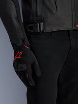 Alpinestars GP Plus R V4 Airflow Leather Jacket, detailed view of black perforated leather and waist adjustment, paired with black gloves featuring red accents and black riding pants, professional motorcycle riding gear