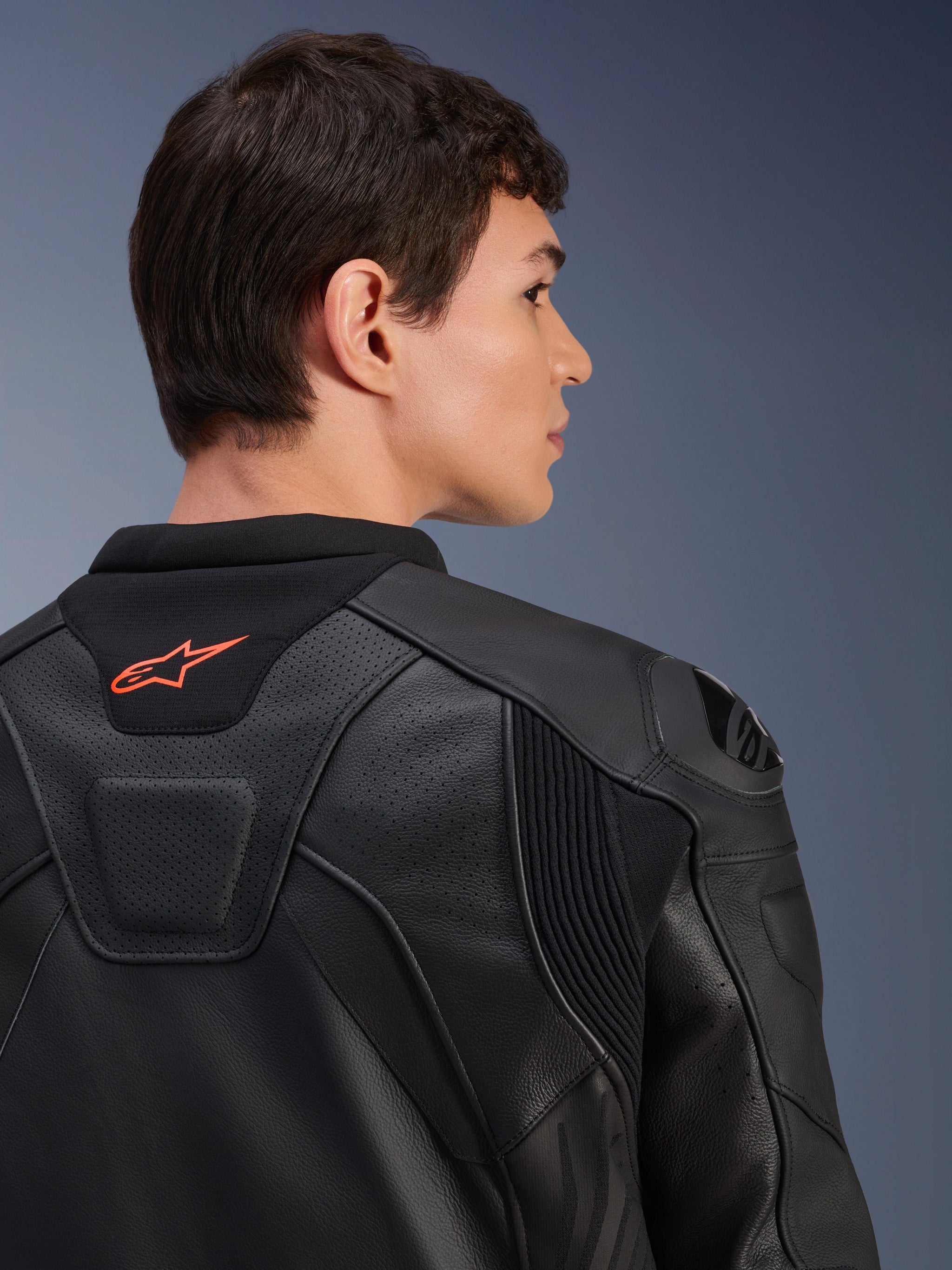 Alpinestars GP Plus R V4 Airflow Leather Jacket, Black, close-up rear view on a model, featuring perforated race-grade leather, technical stretch panels, and a small orange Alpinestars logo on the collar, professional motorcycle riding apparel