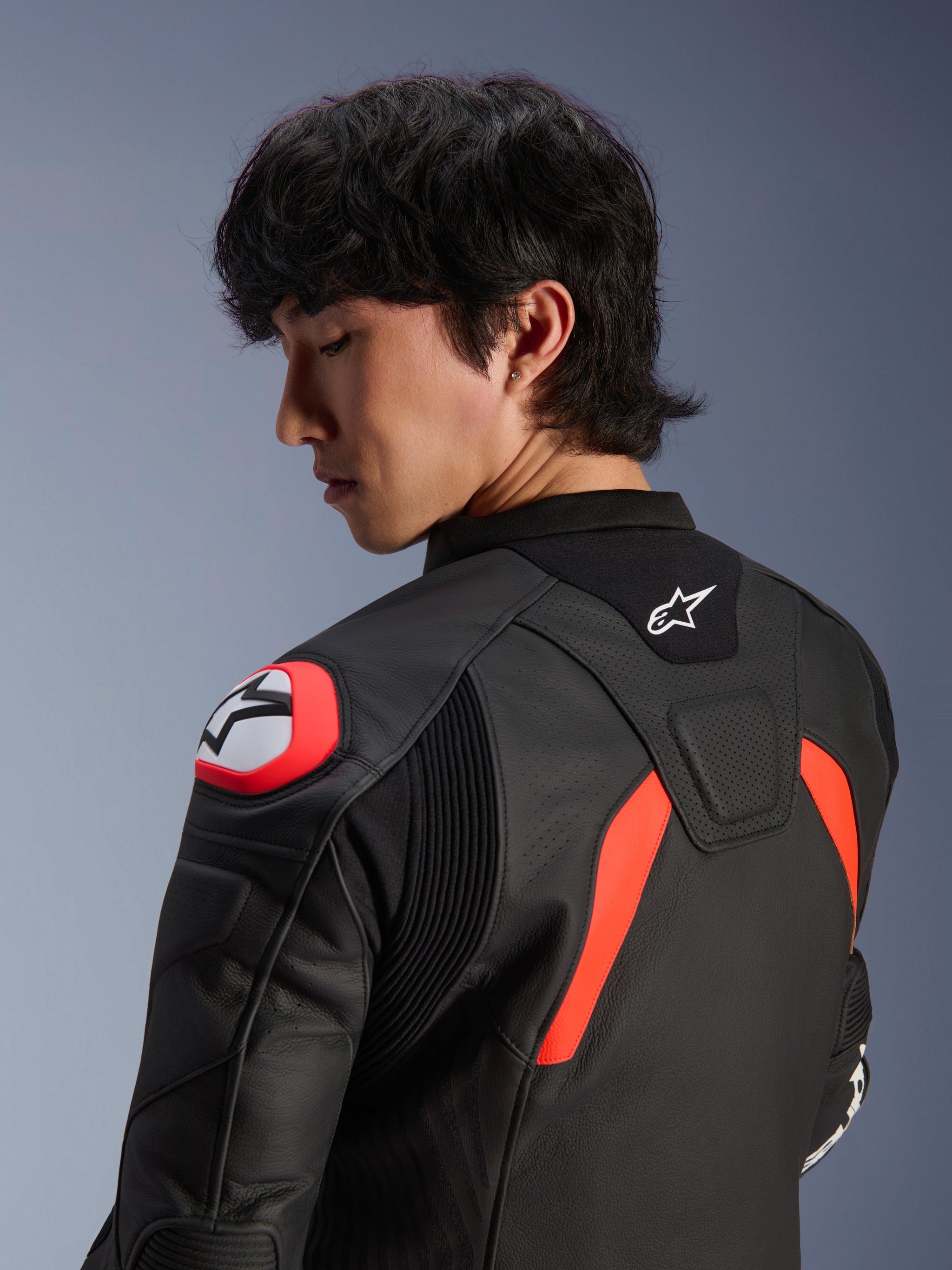 Alpinestars GP Plus R V4 Airflow Leather Jacket, Black with Red Fluo and White accents, close-up view of the back and shoulder on a model, featuring perforated leather zones, Alpinestars logo, and integrated shoulder armor for motorcycle performance.