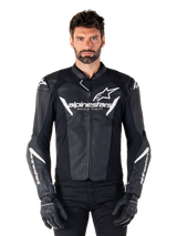 Alpinestars Faster V3 Leather Jacket, Black and White Motorcycle Racing Jacket, featuring bold white logos and 'Racing Ahead' chest text, sleek leather design with angular accents on sleeves, worn with black racing gloves