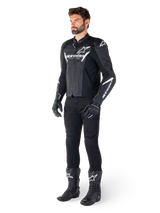 Model wearing Alpinestars Faster V3 Airflow Leather Jacket, Black and White, featuring perforated leather and white Alpinestars logos, paired with black riding pants, gloves, and boots, sport-focused motorcycle gear