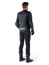 Alpinestars Faster V3 Airflow Leather Jacket, Black and White, rear view showing perforated leather panels and prominent Alpinestars branding on the lower back, worn by a rider with black riding pants, gloves, and boots.