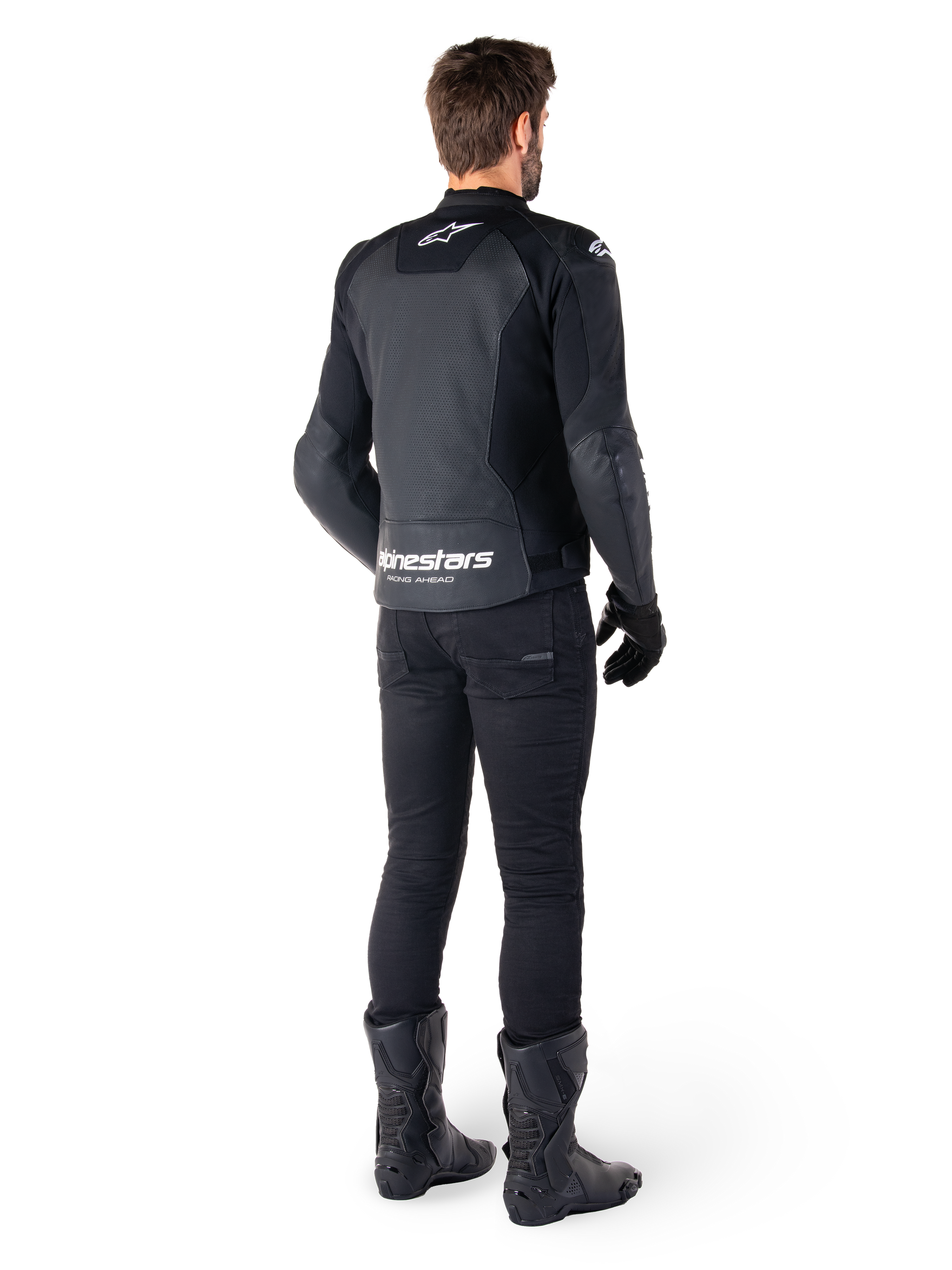 Alpinestars Faster V3 Airflow Leather Jacket, Black and White, rear view showing perforated leather panels and prominent Alpinestars branding on the lower back, worn by a rider with black riding pants, gloves, and boots.