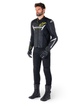 Male rider wearing the Alpinestars Faster V3 Airflow Leather Jacket in Black White and Yellow Fluo, paired with black motorcycle pants and boots, featuring perforated leather panels, white logo details, and neon yellow accents, professional sport riding gear