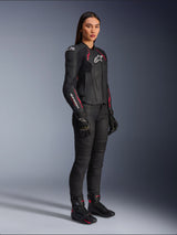 Alpinestars Woman Stella Dusk Leather Jacket, Black Diva Pink and White, worn by a female model with black motorcycle pants and boots, featuring a sleek leather construction with pink detailing and white branding.
