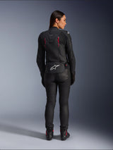 Alpinestars Stella Dusk Leather Jacket, rear view, black leather with Diva Pink and White accents, features white Alpinestars logo on lower back and pink vent details, worn with black riding pants and boots, premium sport motorcycle gear for women
