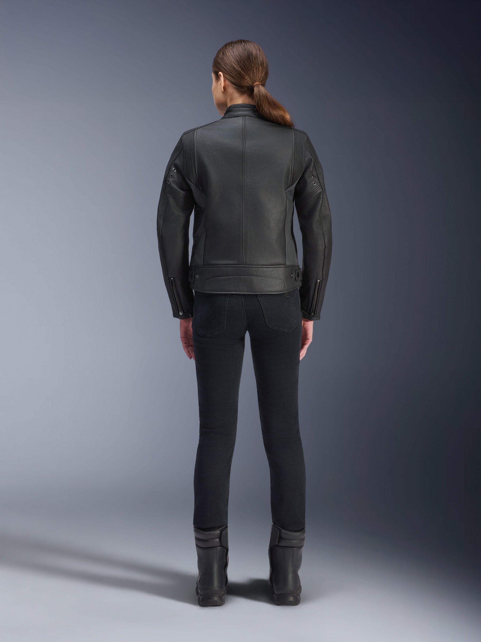 Alpinestars Stella Dyno Leather Jacket, Women's Motorcycle Jacket, Black, rear view highlighting the tailored bovine leather construction, minimalist heritage design, worn with black riding pants and boots for an urban motorcycle look