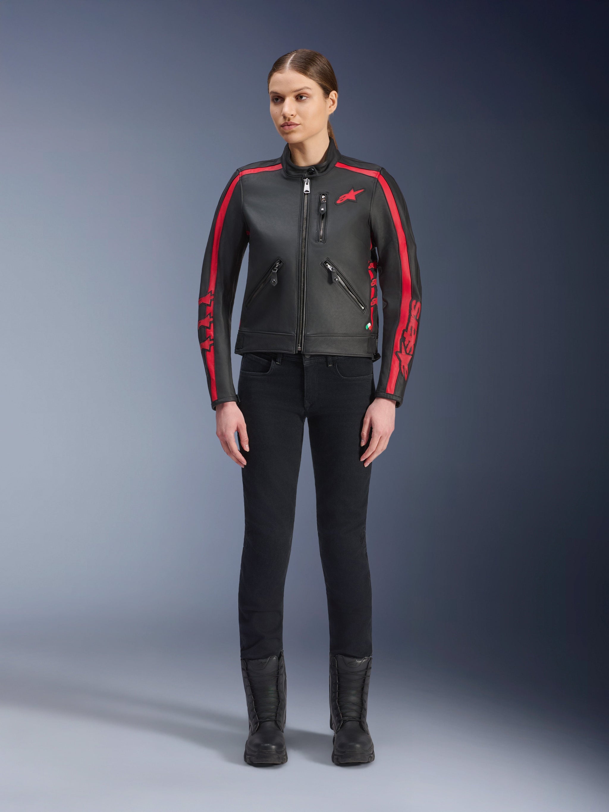Alpinestars Stella Dyno Leather Jacket, Women's Motorcycle Jacket, Black and Haute Red, featuring red racing stripes on shoulders and sleeves, red star logo on chest, worn with black slim-fit pants and boots, premium bovine leather with a modern heritage design