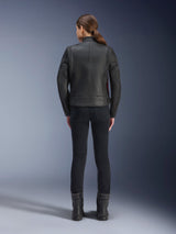 Rear view of a woman wearing the Alpinestars Stella Dyno Leather Jacket, Black with Haute Red accents, paired with slim-fit black pants and black boots, modern heritage leather motorcycle jacket design.