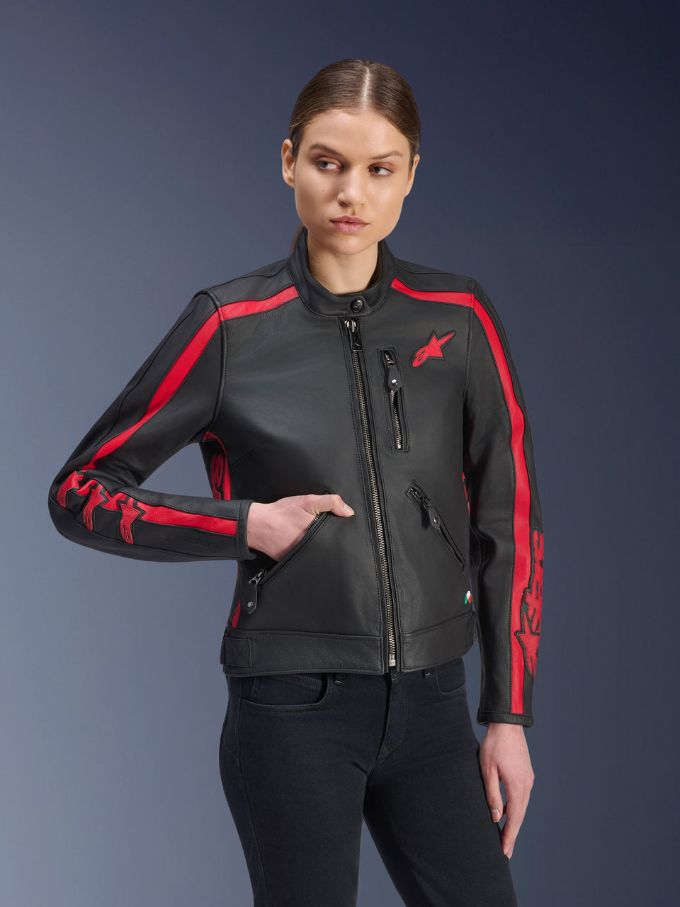 Alpinestars Stella Dyno Leather Jacket, Women's Motorcycle Jacket, Black Haute Red, worn by a model with black jeans, featuring red racing stripes on shoulders and sleeves with bold branding, premium leather construction, heritage-inspired design for urban riding