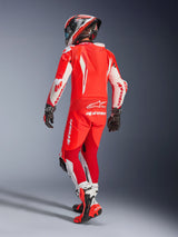 Alpinestars GP Tech V5 One Piece Leather Suit, Red Fluo Bright Red and White, rear view of a motorcyclist in full racing gear, featuring an aerodynamic hump and white panels on sleeves and legs, paired with a matching helmet and red racing boots, professional track performance design.