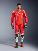 Alpinestars GP Tech V5 One Piece Leather Suit, professional racing suit in Red Fluo and Bright Red with white accents, worn by a rider with matching boots and gloves, featuring an aerodynamic speed hump, premium leather construction, and advanced protective armor for track performance.