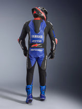 Alpinestars Yamaha GP-R7 One Piece Leather Suit, back view of a motorcycle rider in full racing gear, Metallic Blue and Black with White and Red accents, featuring Yamaha and GYTR branding on the aerodynamic hump, worn with matching blue boots and a racing helmet.