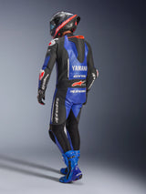 Alpinestars Yamaha GP-R7 One Piece Leather Suit, Metallic Blue Black and White, Rear view showing aerodynamic race hump and Yamaha branding, worn with matching blue racing boots and helmet, professional performance leather suit for track racing