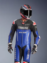 Yamaha GP-R7 One Piece Leather Suit, Metallic Blue and Black with White and Red accents, worn with a matching helmet and racing gloves, featuring YAMAHA and GYTR branding, perforated leather panels, and Alpinestars logos, professional motorcycle racing apparel.