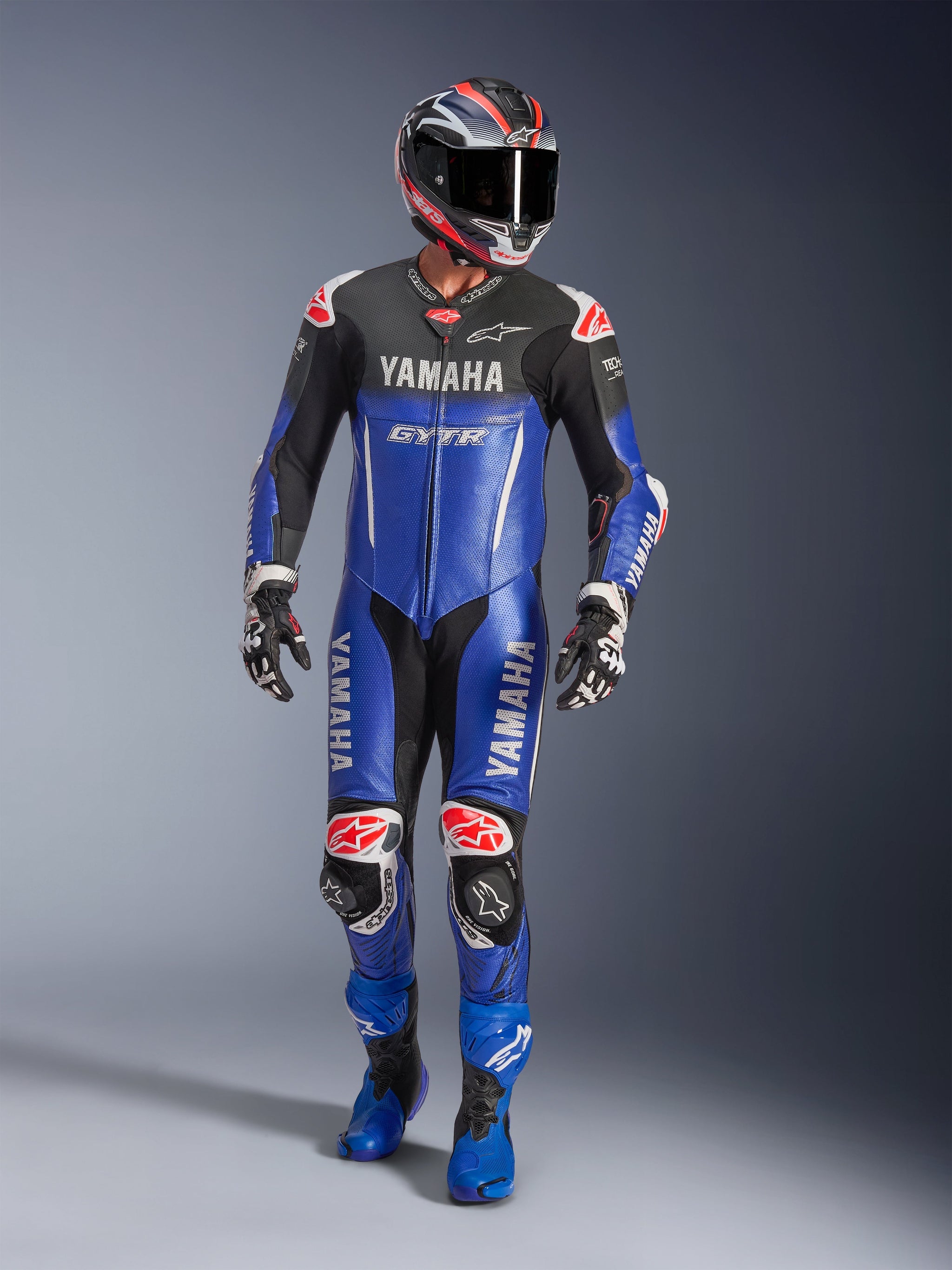 Yamaha GP-R7 One Piece Leather Suit, Motorcycle Racing Suit, Metallic Blue and Black, Red and White accents, features Yamaha and GYTR branding, worn with matching helmet, racing gloves, and blue boots, professional performance gear