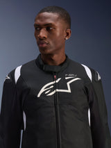 Alpinestars T-SP 1 V2 Waterproof Jacket worn by a model, black and white textile motorcycle jacket, large white Alpinestars logo and T-SP-1 branding on the chest, sporty design with protective shoulder sliders