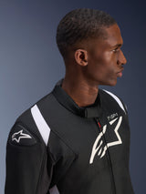 Alpinestars T-SP 1 V2 Waterproof Jacket, Black and White, profile shot of a male model wearing the jacket, featuring the Alpinestars logo on the shoulder slider and chest, 'T-SP-1' branding, and white accents on the shoulders.