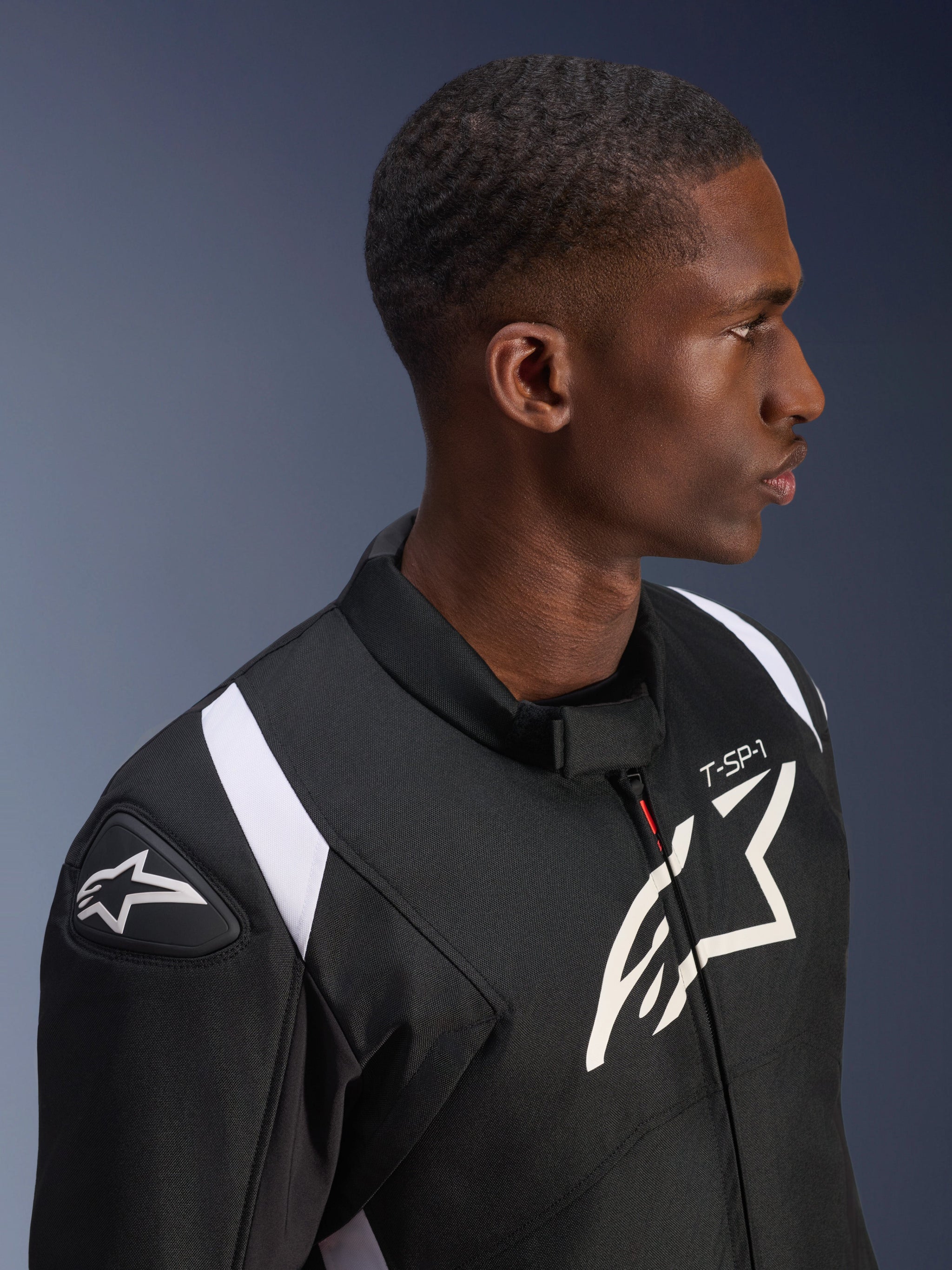 Alpinestars T-SP 1 V2 Waterproof Jacket, Black and White, profile shot of a male model wearing the jacket, featuring the Alpinestars logo on the shoulder slider and chest, 'T-SP-1' branding, and white accents on the shoulders.