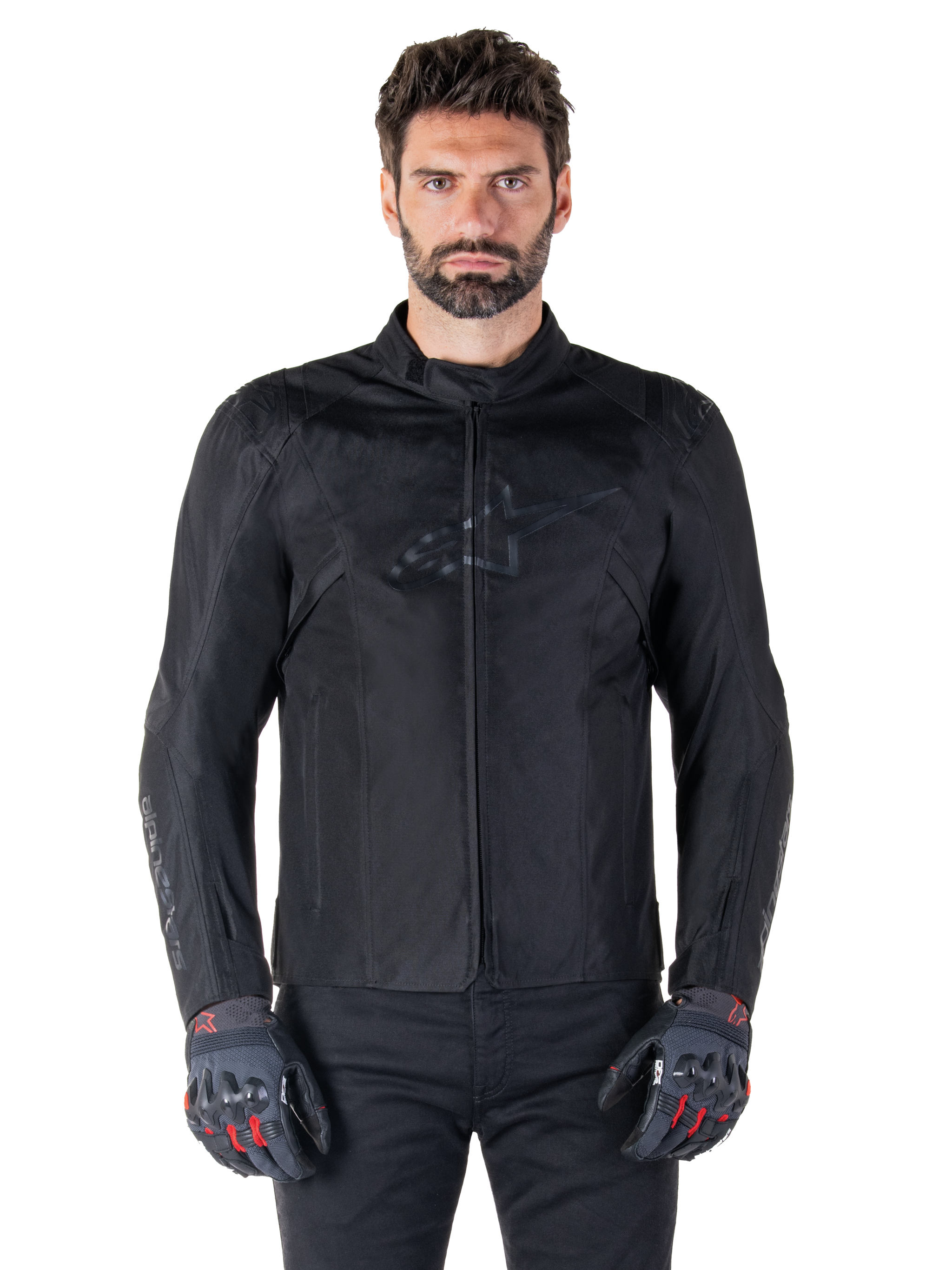 Alpinestars T-SPS V2 Waterproof Jacket, Black motorcycle textile jacket, worn by rider with black and red gloves, featuring a high collar, zippered front, and subtle chest logo, waterproof protection for sport and urban riding