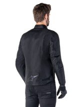 Alpinestars T-SPS V2 Waterproof Jacket, Black, rear view on a male model, featuring a reflective star logo on the lower back, extended back profile, and waist adjustment straps, paired with black riding pants and gloves