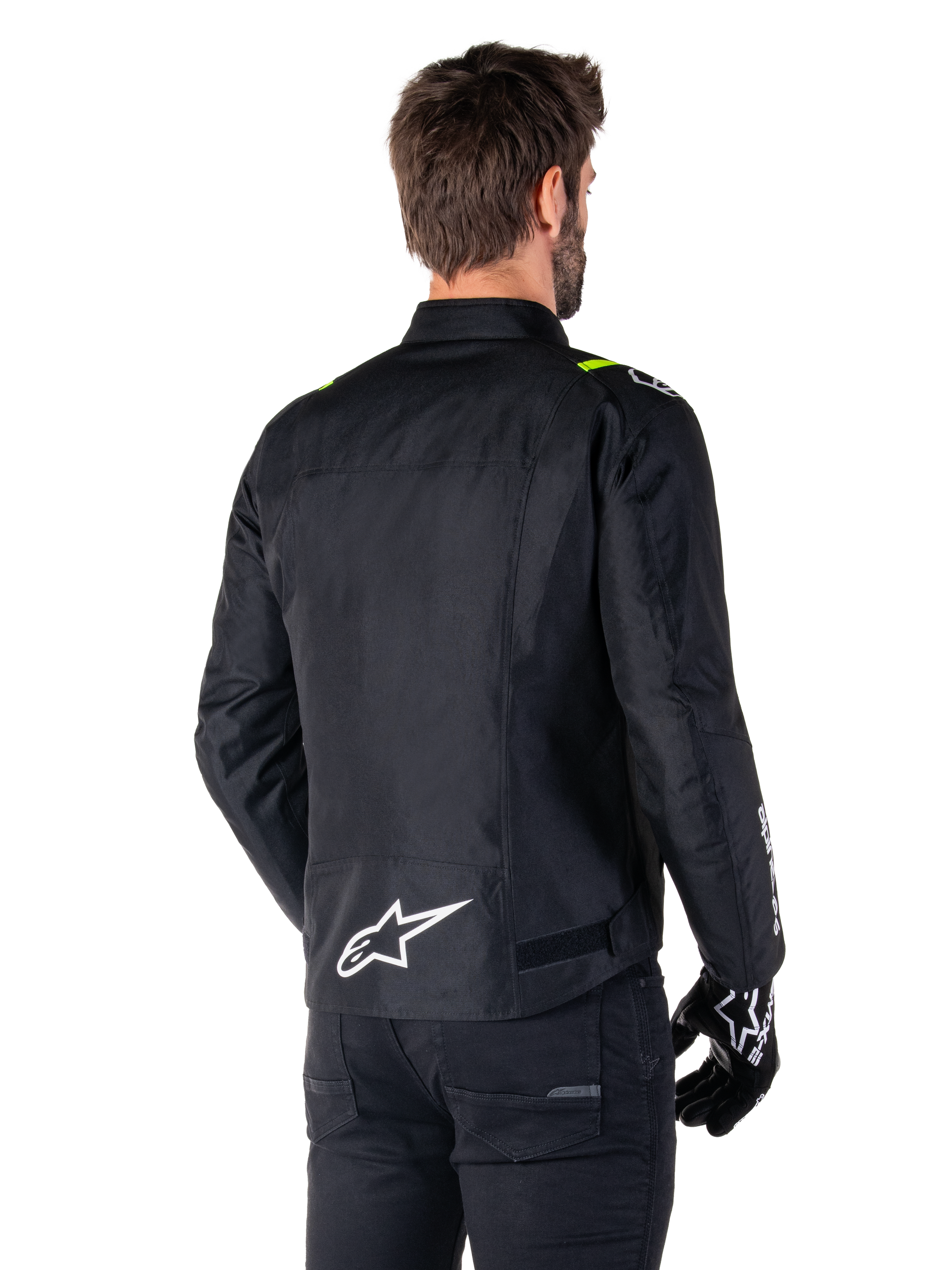 Alpinestars T-SPS V2 Waterproof Jacket, Black White Yellow Fluo, rear view of male model wearing the textile motorcycle jacket, featuring a white logo on the lower back and yellow fluo accents on the shoulders, paired with black pants and gloves.