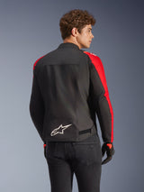 Alpinestars T-SPS V2 Waterproof Jacket in Black and Red, back view on a model, featuring a white Alpinestars logo on the lower back, vibrant red sleeve panels, and a sport-cut silhouette, worn with black gloves and jeans.