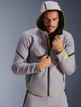 Alpinestars Aeroshell Waterproof Jacket, Mid Gray and Yellow Fluo, sports softshell jacket with a hoodie, worn by a male model with the hood up, featuring black waterproof zippers and fluorescent yellow accents on the cuffs and hem, modern motorsport-inspired design