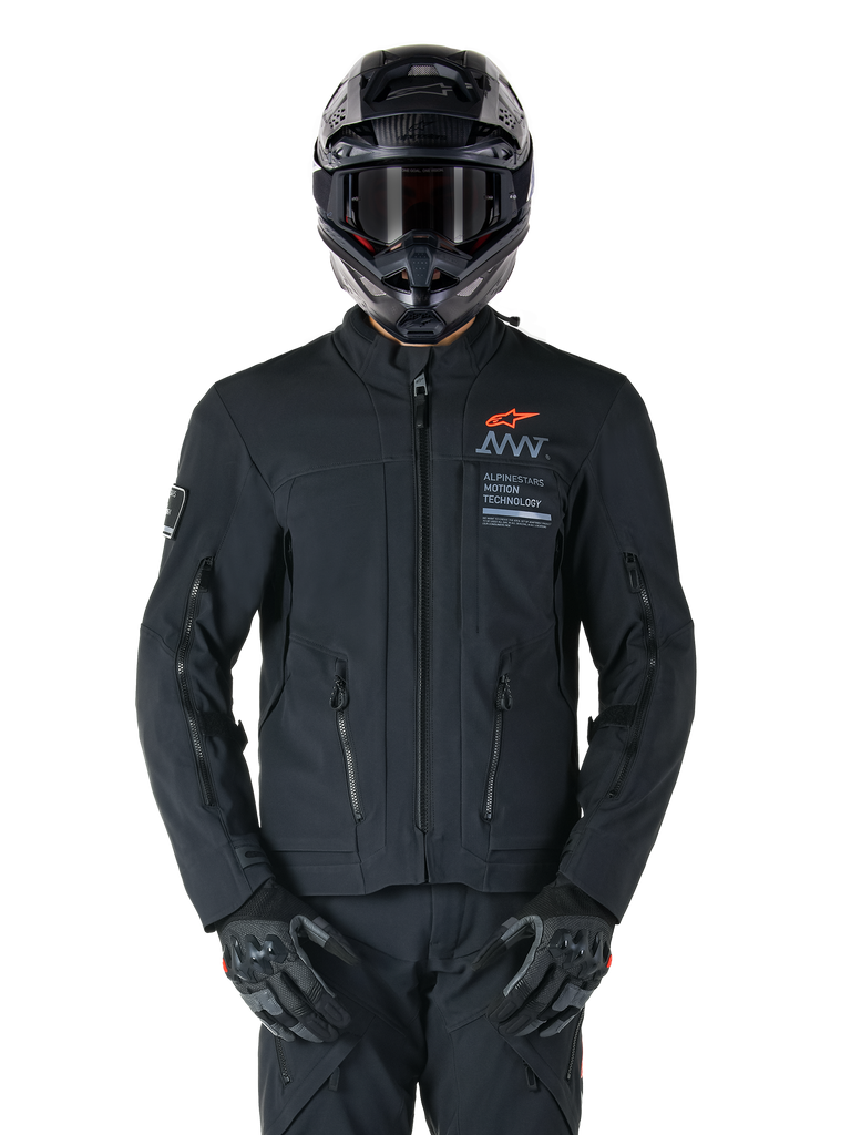Alpinestars AMT-8 Stretch Drystar® XF Jacket, Black Motorcycle Jacket, featuring orange Alpinestars logo and grey AMT branding, high collar with front zipper and vents, worn with black helmet and gloves, protective adventure touring gear