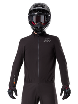 Alpinestars AMT-8 Stretch Drystar® XF Liner, black waterproof motorcycle liner, featuring a front zipper and elasticated waist, AMT logo on the chest and Drystar XF branding on the sleeve, worn with a black helmet and gloves.