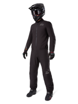 Alpinestars AMT-8 Stretch Drystar® XF Liner, black waterproof motorcycle suit, worn with black helmet, goggles, and gloves, featuring AMT and Drystar XF branding, functional adventure gear for all-weather protection.