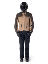 Alpinestars AMT-8 Stretch Drystar® XF Jacket, Adventure Motorcycle Jacket, Dark Brown and Dark Khaki, worn with a black helmet, goggles, black gloves, black pants, and black boots, featuring chest ventilation ports and AMT branding, coordinated gear for adventure touring