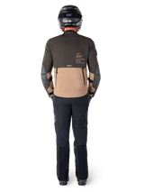 Alpinestars AMT-8 Stretch Drystar® XF Jacket, Adventure Touring Jacket, Dark Brown and Dark Khaki, rear view showing Alpinestars Motion Technology branding on the back, worn with black pants and black full-face helmet, performance stretch textile for adventure motorcycle gear