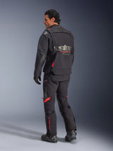 Alpinestars Halo Pro Drystar® XF Laminated Jacket, Adventure Motorcycle Jacket, Black Dark Shadow with red accents, rear view worn with matching pants and boots, featuring grey branding on the back, modular textile design for adventure touring