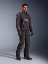 Male rider wearing the Alpinestars Halo Pro Drystar® XF Laminated Jacket in Black Dark Shadow, complete adventure riding gear with matching pants, gloves, and boots, featuring modular asymmetrical front panels and red branding accents.