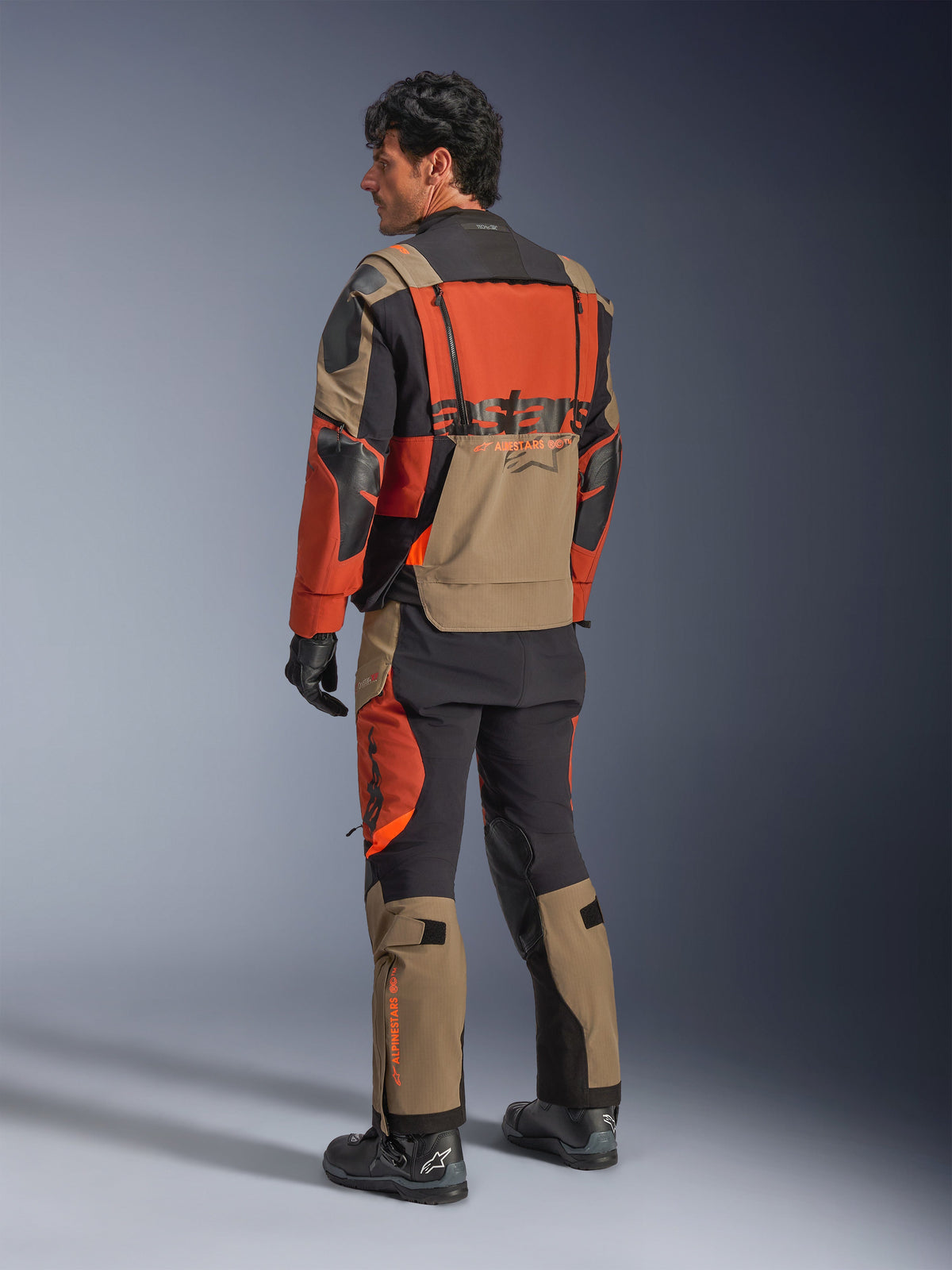 Alpinestars Halo Pro Drystar® XF Laminated Jacket, Walnut Rust Black adventure motorcycle jacket, back view worn with matching pants and black boots, featuring technical 3L stretch material, modular ventilation panels and orange branding on the rear