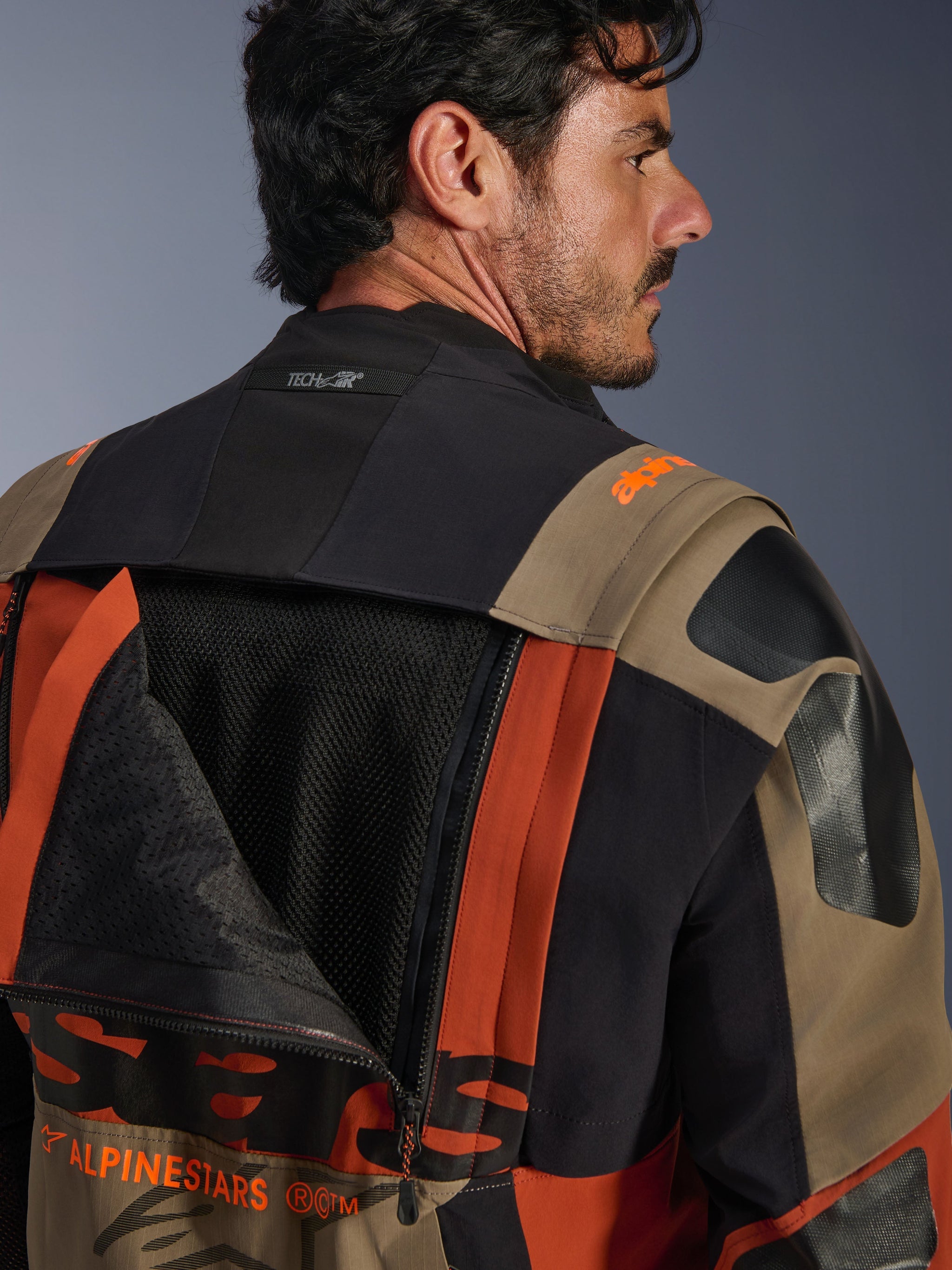 Alpinestars Halo Pro Drystar® XF Laminated Jacket in Walnut Rust Black, close-up back view featuring an unzipped ventilation panel revealing internal mesh, Tech-Air® branding on the collar, and a durable multi-colored textile construction.