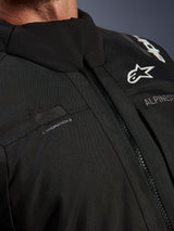 Alpinestars Andes V4 Drystar® Jacket, Black, close-up of chest detail featuring hydration hose loop, waterproof VISLON® front zipper, and Alpinestars logo on durable textile material