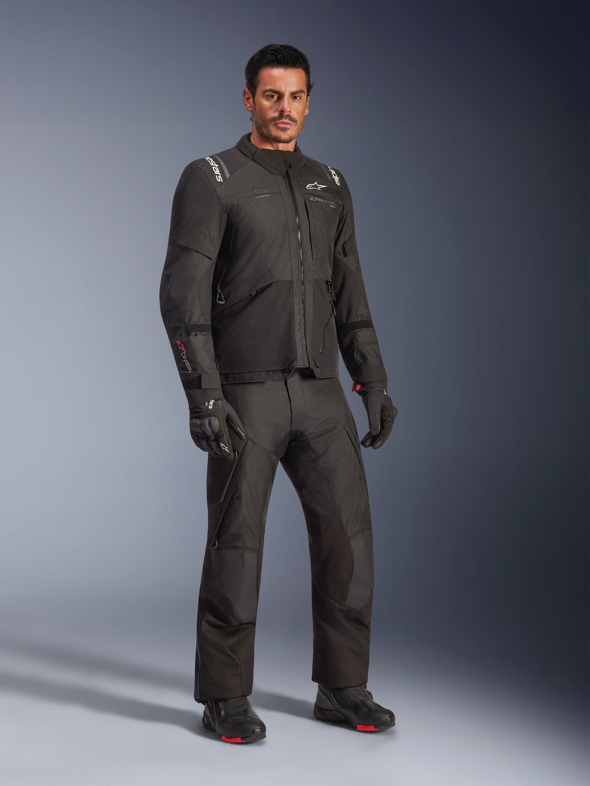 Alpinestars Andes V4 Drystar® Jacket, Black motorcycle gear set, worn by a model, adventure-touring textile jacket and pants, black gloves and boots, studio shot, sleek modern design for all-weather riding
