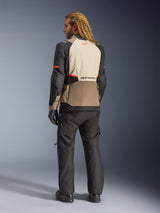 Alpinestars Andes V4 Drystar® Jacket, Walnut Mastic Black, rear view on male model, featuring tan and black reinforced textile panels with orange accents, Alpinestars logo on the back, worn with matching black adventure riding pants and gloves.