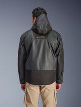 Rear view of a man wearing the Alpinestars Mospher Waterproof Jacket in Black, featuring a hood and durable ripstop textile construction, shown with tan cargo pants, highlighting the MO.ST.EQ. logo on the upper back, urban motorcycle gear design.